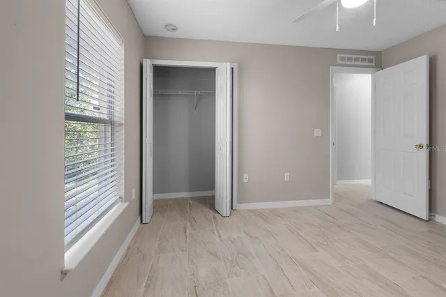 an empty room with wooden floor closet and windows