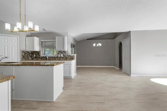 a view of kitchen with granite countertop stove top oven and cabinets