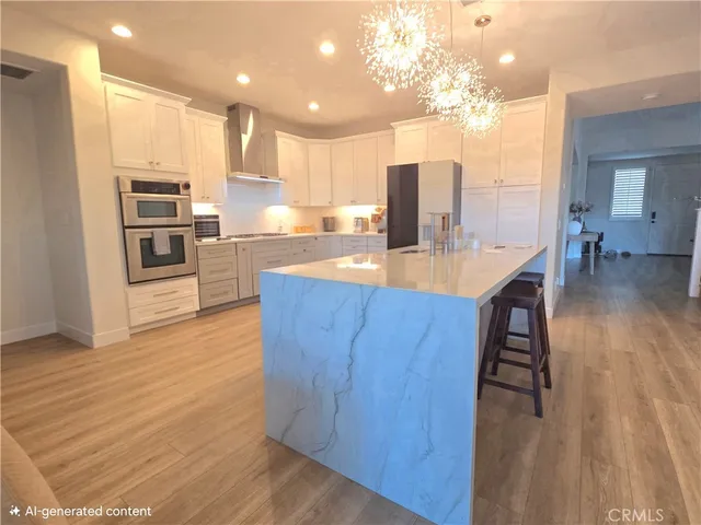 a kitchen with stainless steel appliances kitchen island granite countertop a refrigerator a stove a sink and a oven with wooden floor