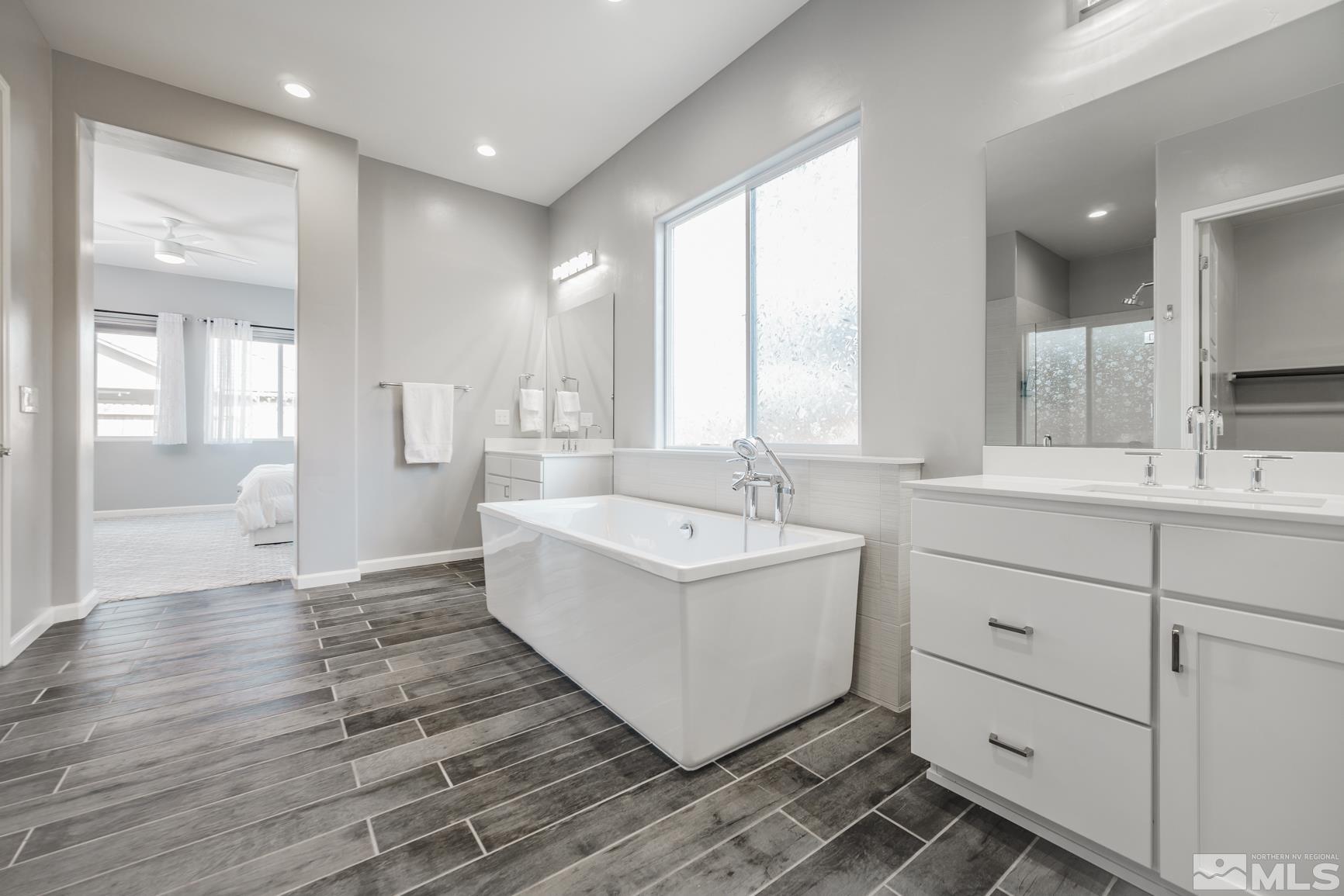 9576 Gazala Lane Reno, NV 89521 - Photo 28 of 40 a bathroom with a double vanity sink a mirror and a bathtub