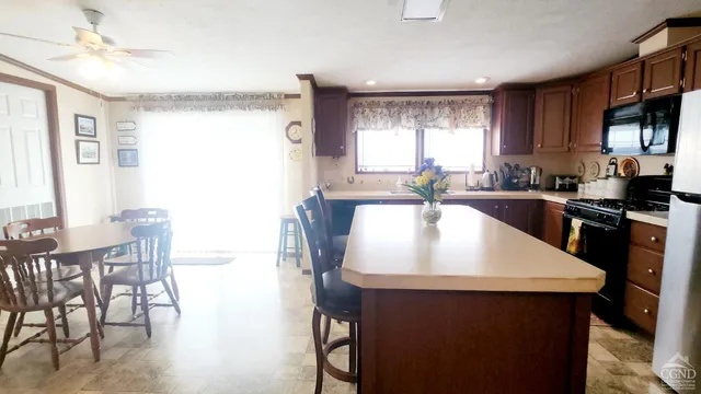 a kitchen with granite countertop a sink a stove a dining table and chairs