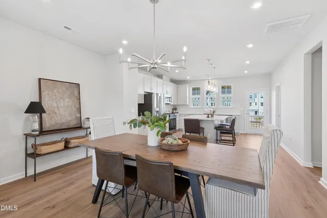a kitchen with stainless steel appliances a table chairs refrigerator and sink