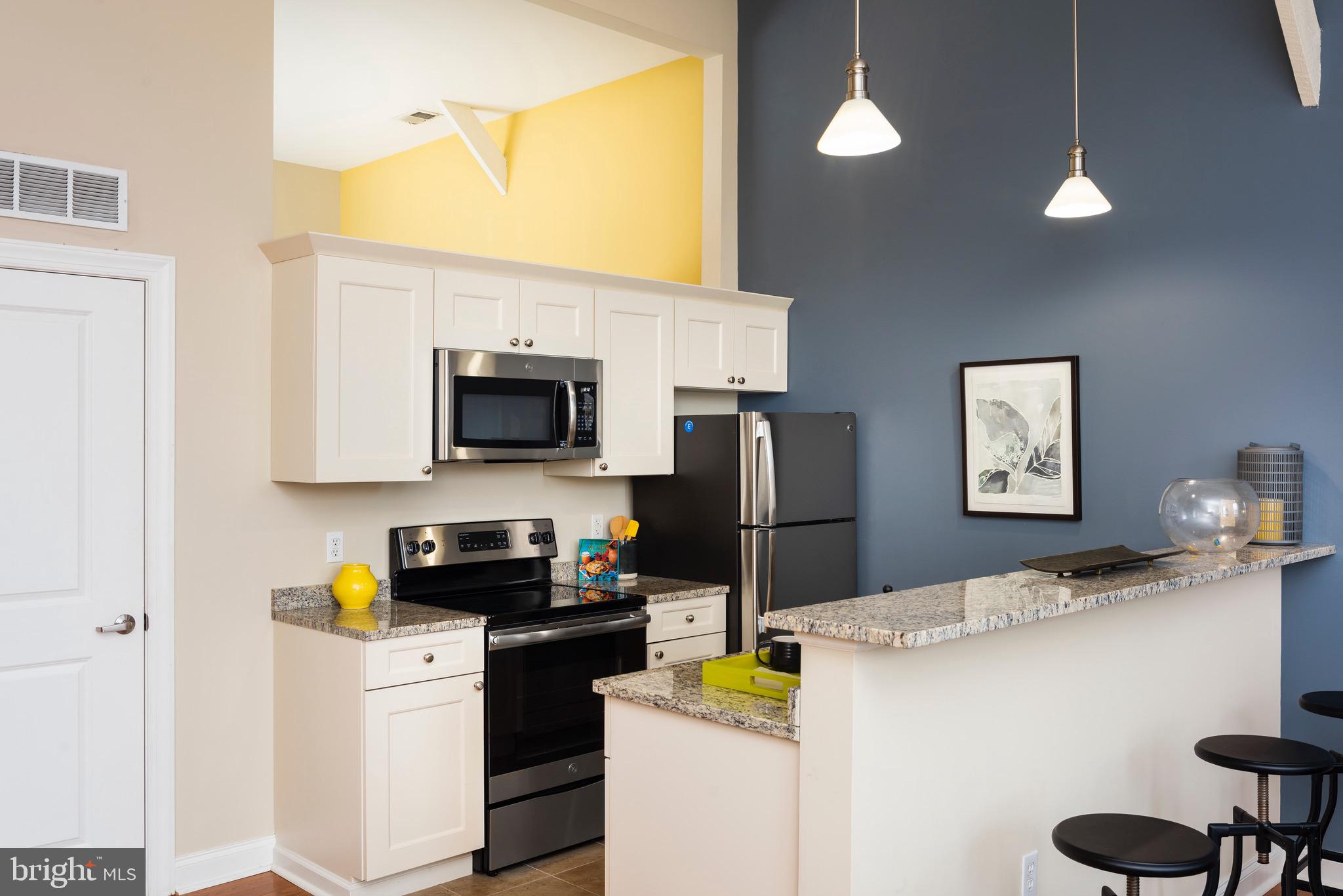 101 Wells Baltimore Md 21230, Unit 1BR Baltimore, MD 21230 - Photo 40 of 46 a kitchen with stainless steel appliances a refrigerator a stove a microwave a dining table and chairs with wooden floor