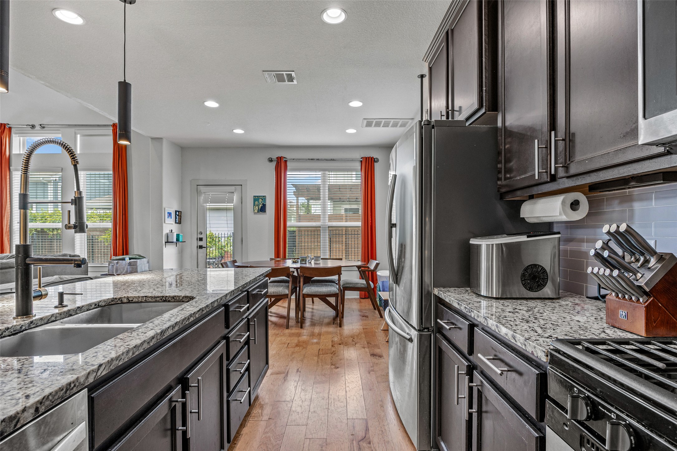 1408 Homespun Road Austin, TX 78745 - Photo 10 of 20 Granite counters and rich cabinetry define this contemporary kitchen with an inviting dining space beyond.