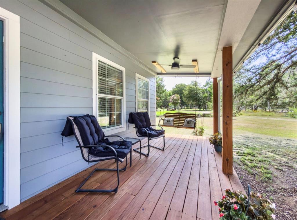 14275 Gholson Road Gholson, TX 76705 - Photo 4 of 22 Covered wood-finish porch featuring a ceiling fan with integrated lighting, wood support columns, and light gray horizontal siding