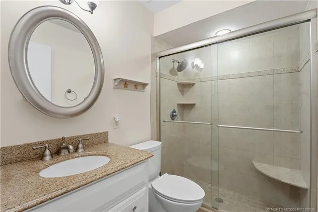 a bathroom with a granite countertop sink a toilet and a mirror