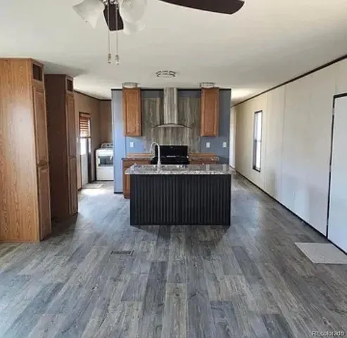 a living room with stainless steel appliances kitchen island hardwood floor and a ceiling fan