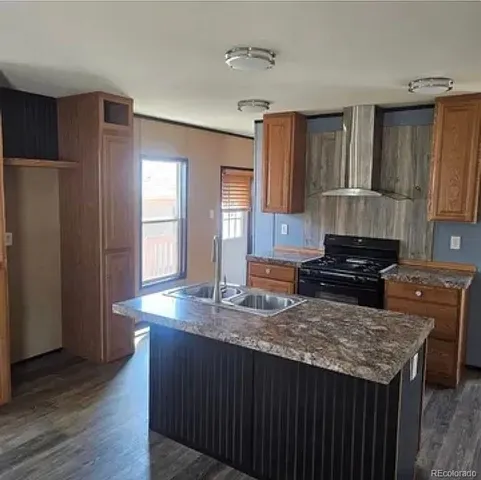 a kitchen with a stove a sink a refrigerator and wooden floor