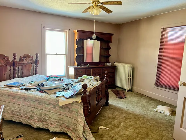 a bedroom with a bed a dresser and next to a window