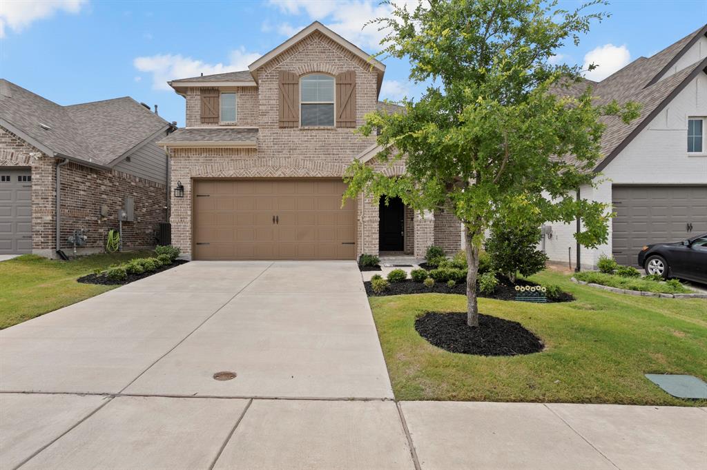 Traditional-style home featuring brick siding, concrete driveway, a front yard, and an attached garage