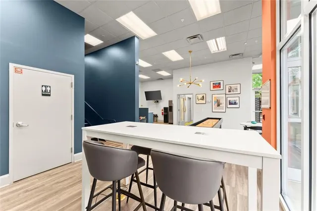 a room with stainless steel appliances kitchen island a table chairs and a refrigerator