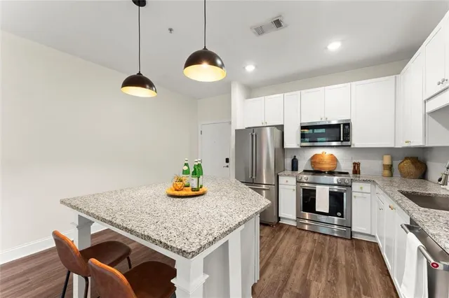 a kitchen with stainless steel appliances granite countertop a stove refrigerator a microwave oven a sink with island and chairs