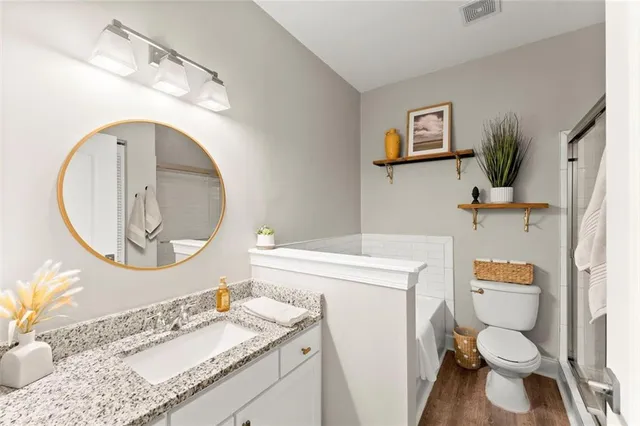 a bathroom with a granite countertop toilet sink mirror vanity and vanity