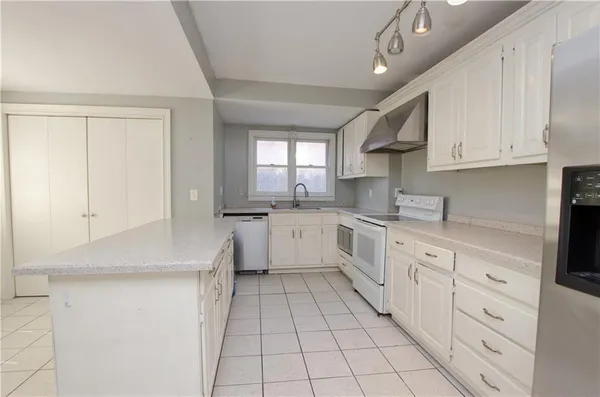 a kitchen with white cabinets appliances and a window