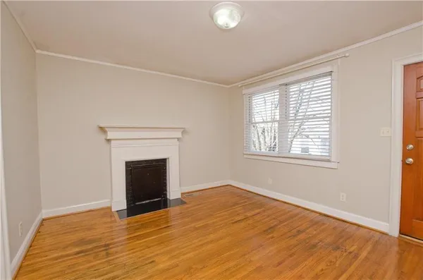 an empty room with wooden floor fireplace and windows