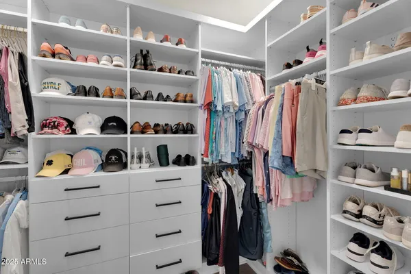 a view of walk in closet with clothes and shoes