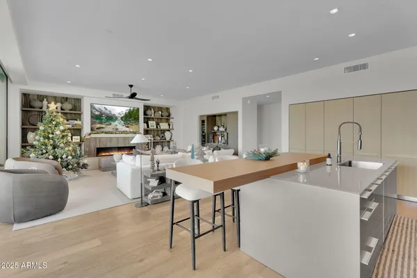 a living room with stainless steel appliances furniture a rug and a kitchen view