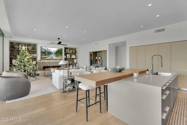 a living room with stainless steel appliances furniture a rug and a kitchen view