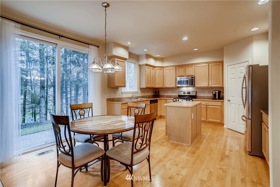 111 203rd Street Southeast Bothell, WA 98012 - Photo 8 of 31 a kitchen with a table chairs refrigerator and microwave
