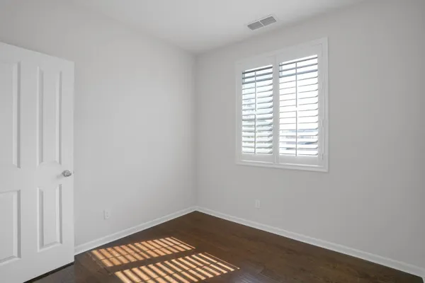 a bedroom with a bed a dresser and next to a window