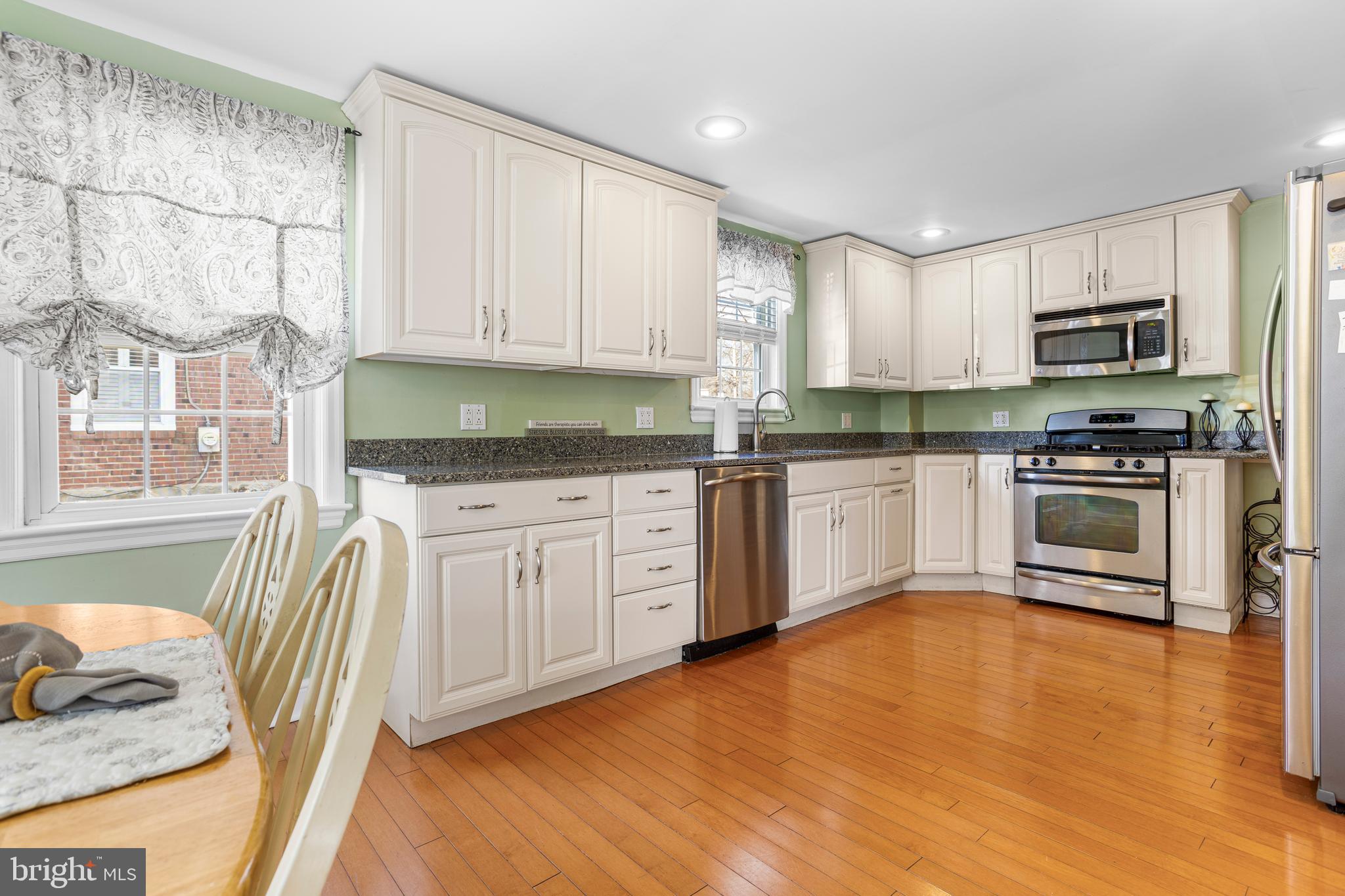 351 Shaw Road Ridley Park, PA 19078 - Photo 8 of 33 a kitchen with stainless steel appliances granite countertop a stove top oven a sink dishwasher and white cabinets with wooden floor