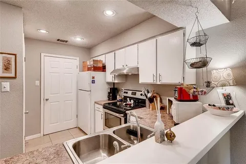 a kitchen with a sink a stove and white cabinets
