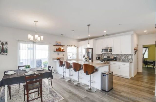 a kitchen with stainless steel appliances kitchen island granite countertop a dining table and chairs