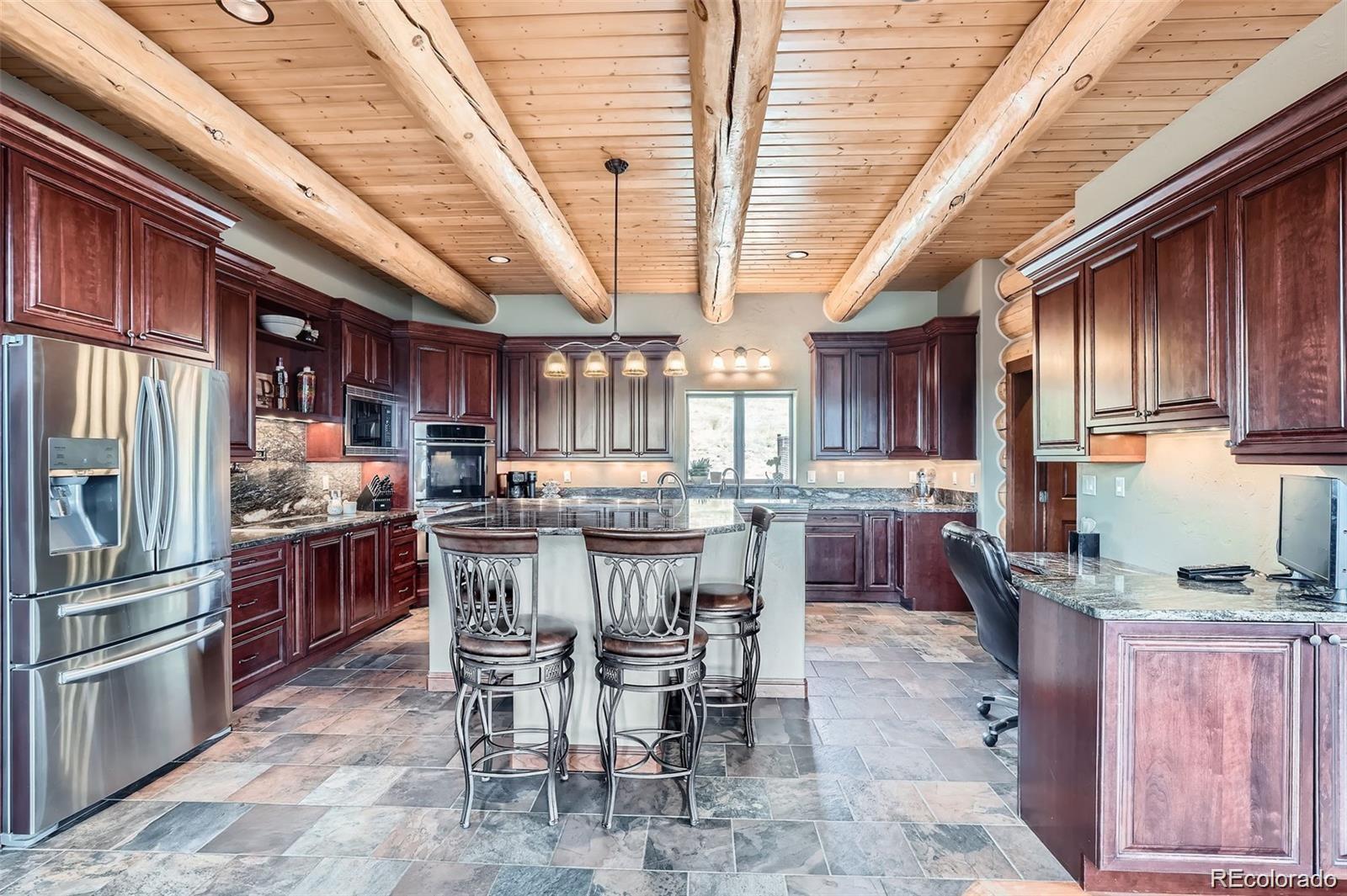 401 Raptor Point Golden, CO 80403 - Photo 26 of 40 a kitchen with stainless steel appliances kitchen island granite countertop a table chairs microwave and stove top oven