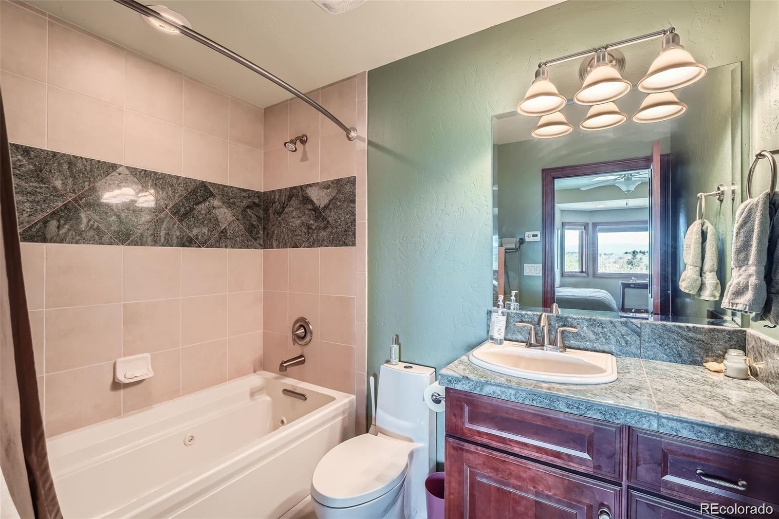 401 Raptor Point Golden, CO 80403 - Photo 36 of 40 a bathroom with a granite countertop sink a toilet a mirror and bathtub