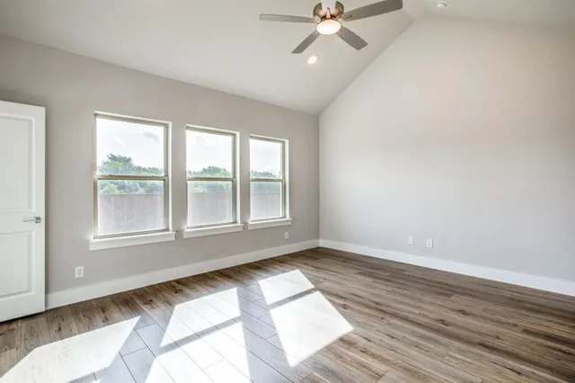 an empty room with wooden floor fan and windows
