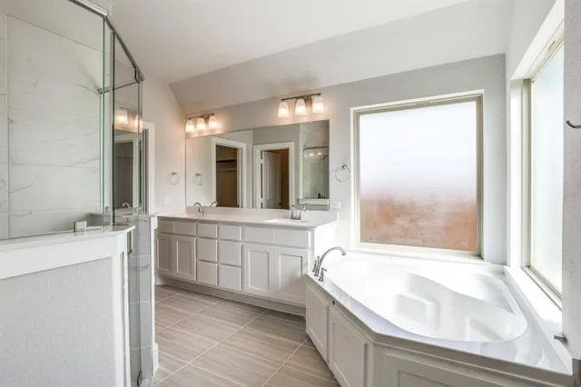 a bathroom with a granite countertop tub sink and mirror