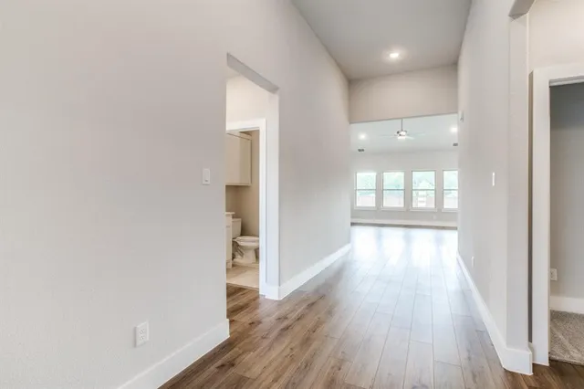 a view of a hallway with wooden floor and a bathroom