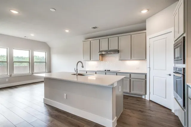 a kitchen with stainless steel appliances granite countertop a sink a stove and a refrigerator