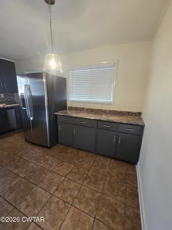 a view of kitchen with granite countertop cabinets and refrigerator