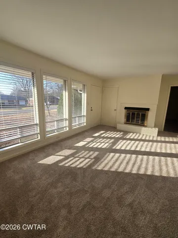 a view of an empty room with a fireplace and a window
