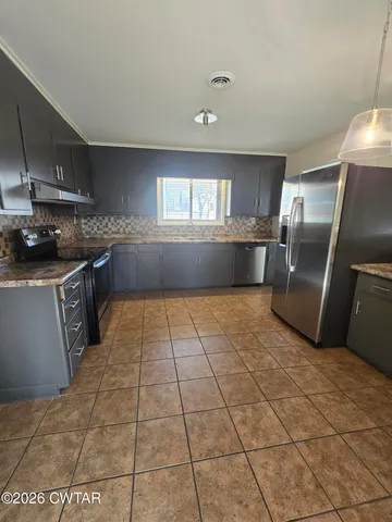 a kitchen with granite countertop a stove a sink and a refrigerator