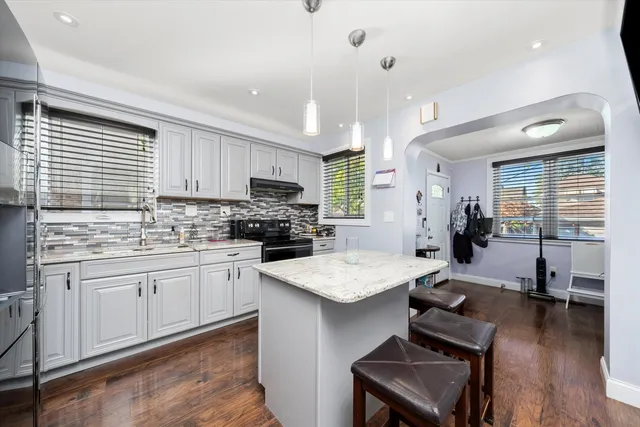 a kitchen with stainless steel appliances granite countertop a sink dishwasher a stove a refrigerator a microwave oven with white cabinets and wooden floor