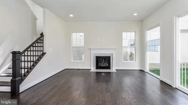 an empty room with wooden floor a fireplace and windows