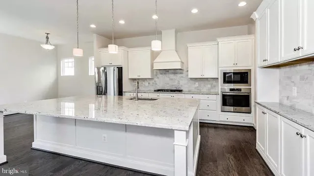 a large kitchen with kitchen island a large counter top stainless steel appliances and cabinets