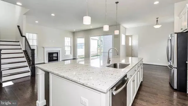 a kitchen with granite countertop a sink a counter top space and stainless steel appliances