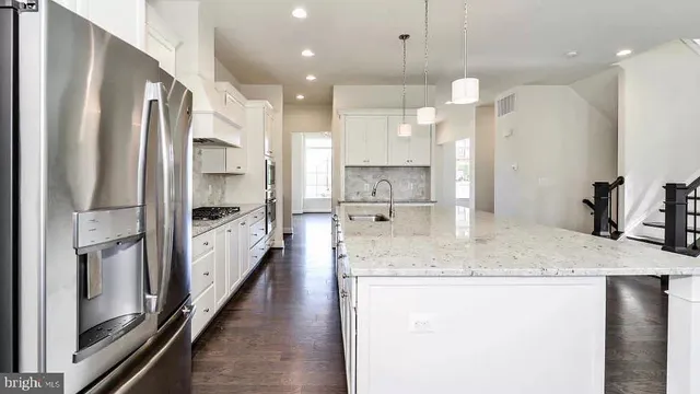 a kitchen with stainless steel appliances granite countertop a refrigerator a oven a sink and a stove