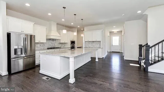 a large kitchen with stainless steel appliances refrigerator a stove and wooden floor