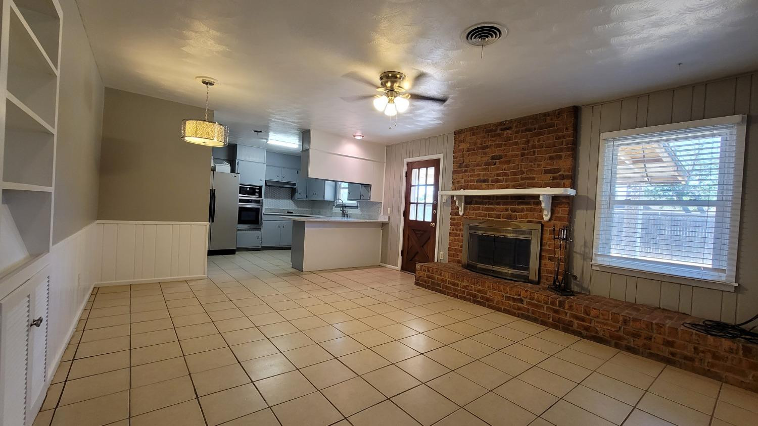5430 13th Street Lubbock, TX 79416 - Photo 15 of 26 a view of a livingroom with a fireplace a ceiling fan and windows