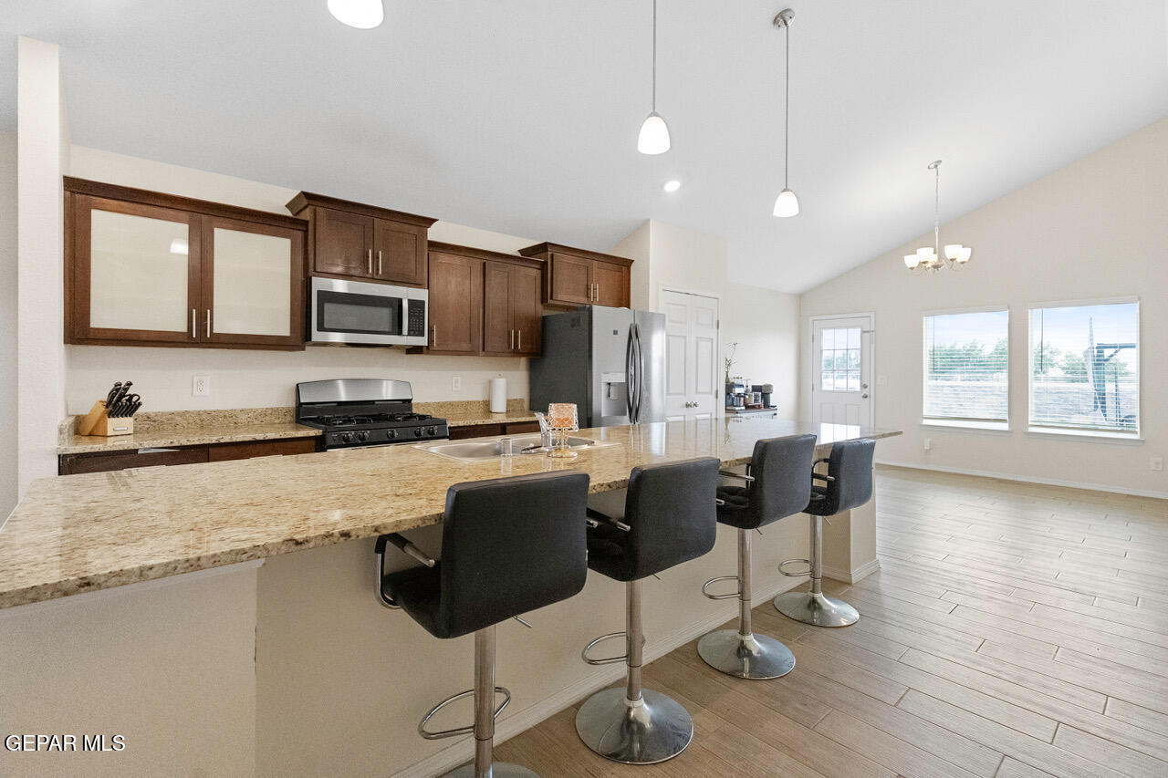 11288 Santa Barbara Socorro, TX 79927 - Photo 8 of 31 a kitchen with stainless steel appliances granite countertop a stove top oven a sink dishwasher a dining table and chairs with wooden floor