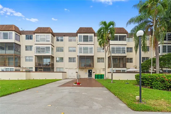 a front view of multi story residential apartment building with yard and green space