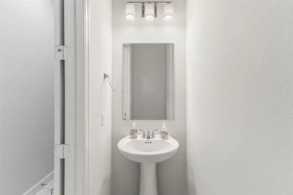 a view of a white house with a large pool and a lawn chairs under an umbrella