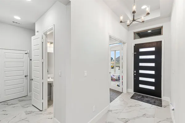 a view of a hallway with wooden floor and chandelier