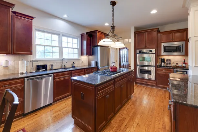 a kitchen with stainless steel appliances granite countertop a stove a sink and a refrigerator