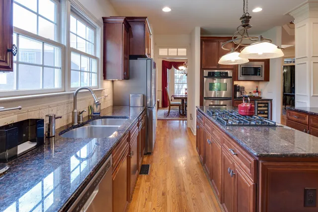 a kitchen with stainless steel appliances granite countertop sink stove and wooden cabinets