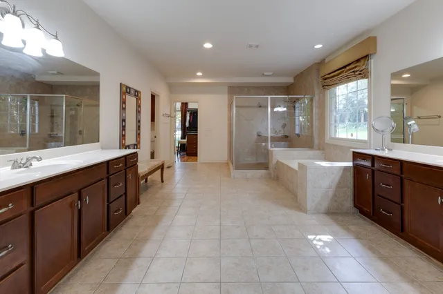 a large bathroom with a double vanity sink a large mirror and a bathtub